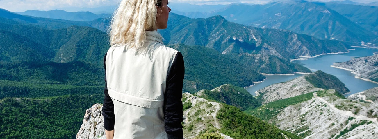 Woman packing a water bottle in the front pocket of a SCOTTeVEST Q.U.E.S.T safari vest.