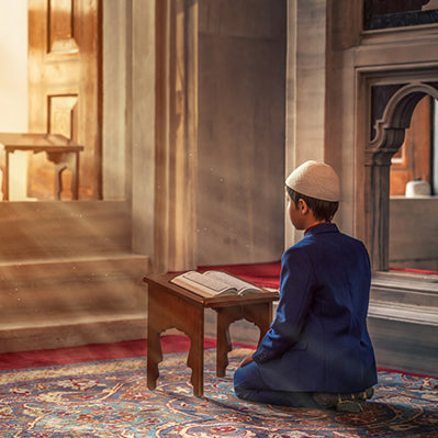 Enfant musulman priant à genoux devant un Coran, illuminé par des rayons du Soleil à travers une fenêtre