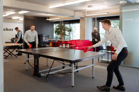 Dvojica kolega igraju stoni tenis u kancelariji