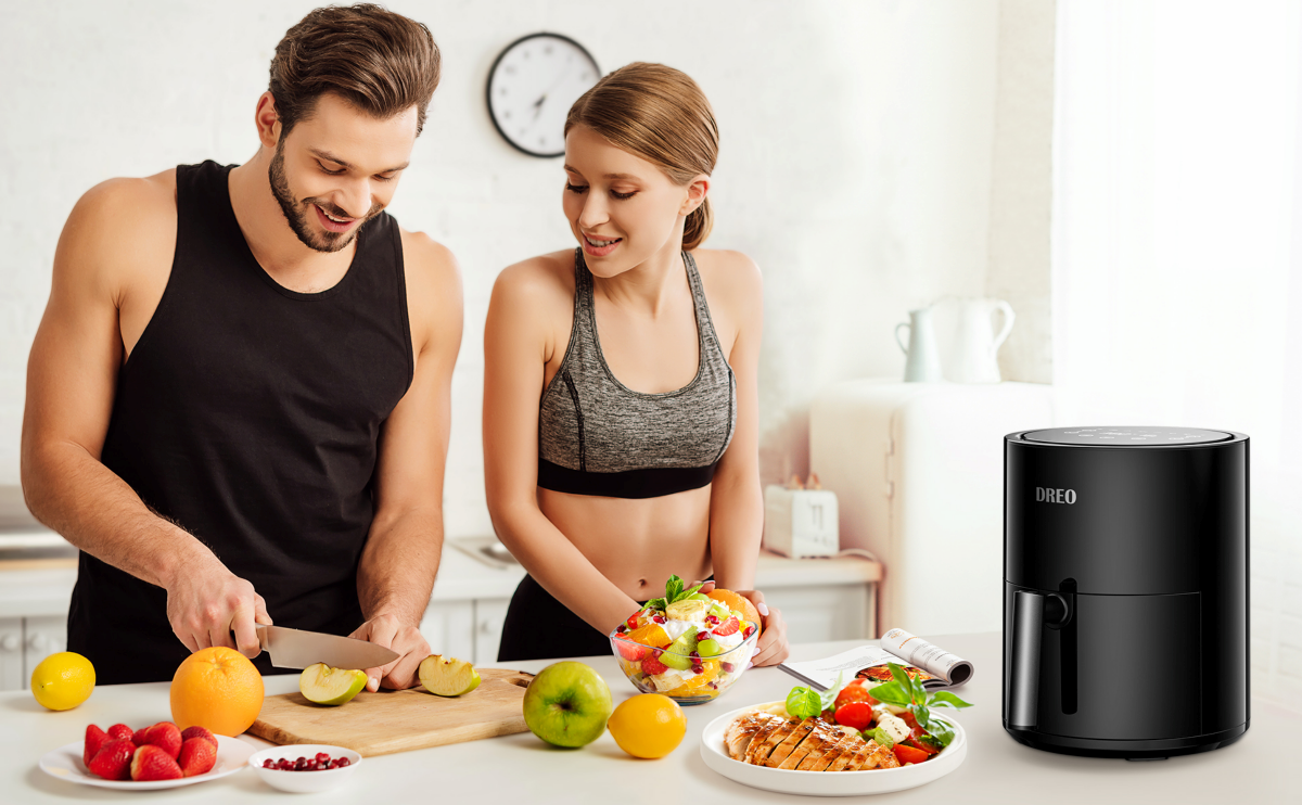 A man and a women prepare the food with a Dreo air fryer on the desk