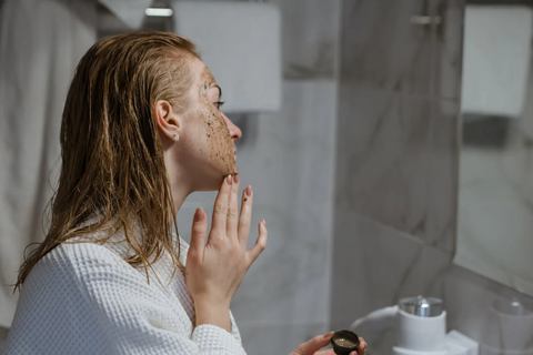 A woman scrubbing her face with an exfoliant