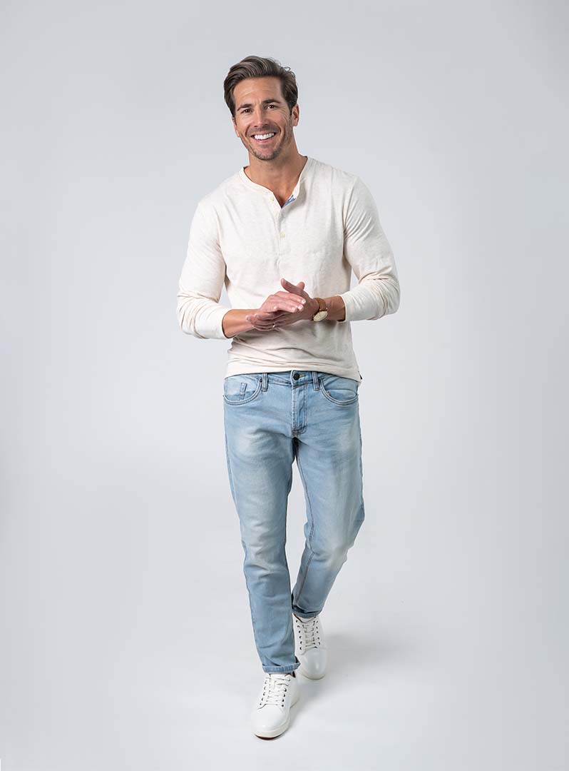 Man poses on white background with Henley shirt, a men’s closest essential