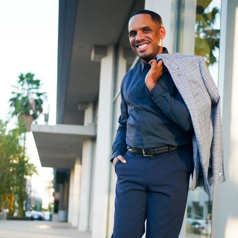 A man in business-casual attire walking along a sidewalk outside buildings