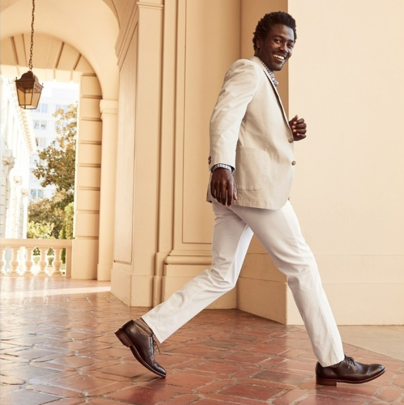 A man in versatile clothing, including a light sport jacket walks through a hall