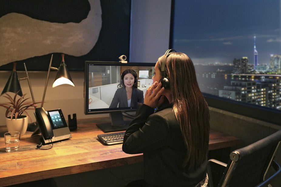 A person wearing a wireless headset while using Microsoft Teams on a computer