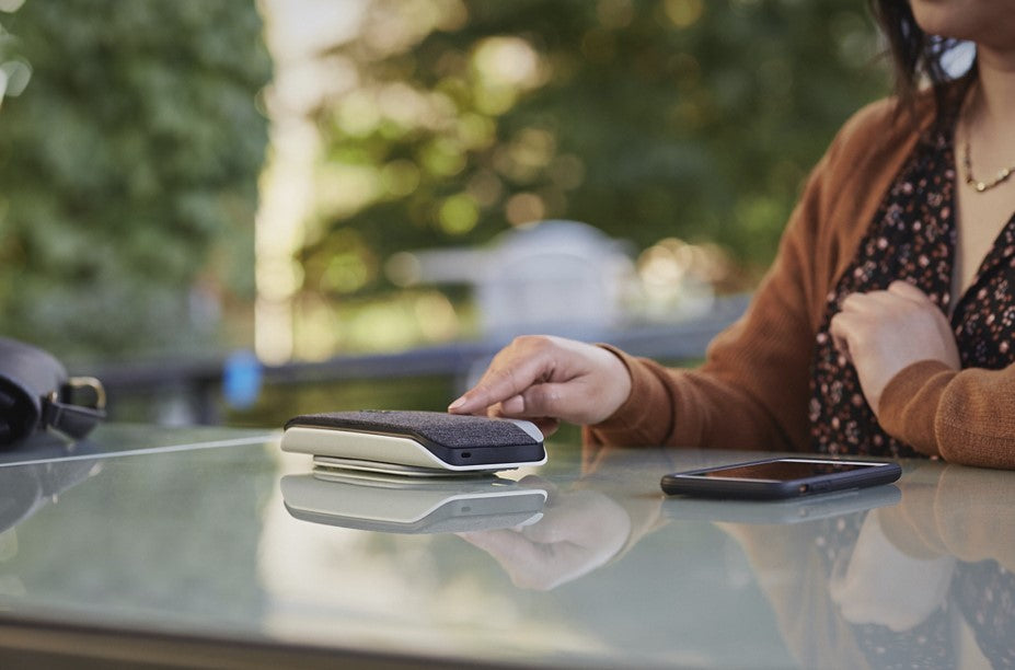 A person using a Poly Plantronic portable speakerphone in a mobile work environment