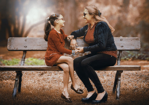 A woman and girl talk on a park bench; in sympathy cards messages