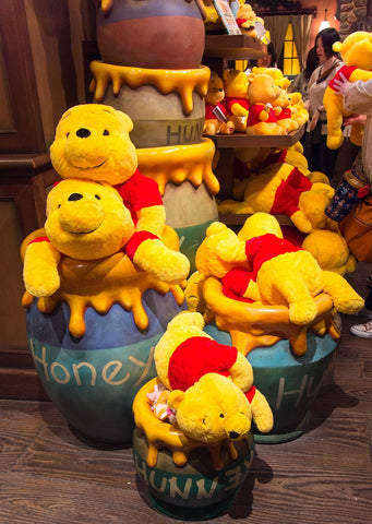 A pile of Winnie the Pooh stuffed animals photographed at a Disney Store