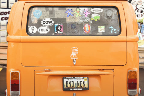 The back of an orange van; it's covered in stickers
