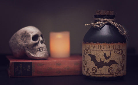 A skull and a potion bottle sit on either side of a candle.
