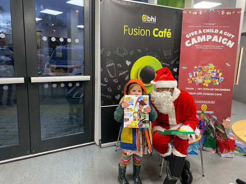 A child wearing a warm winter coat, beaming as they hold up a new action figure at the Chapeltown event.