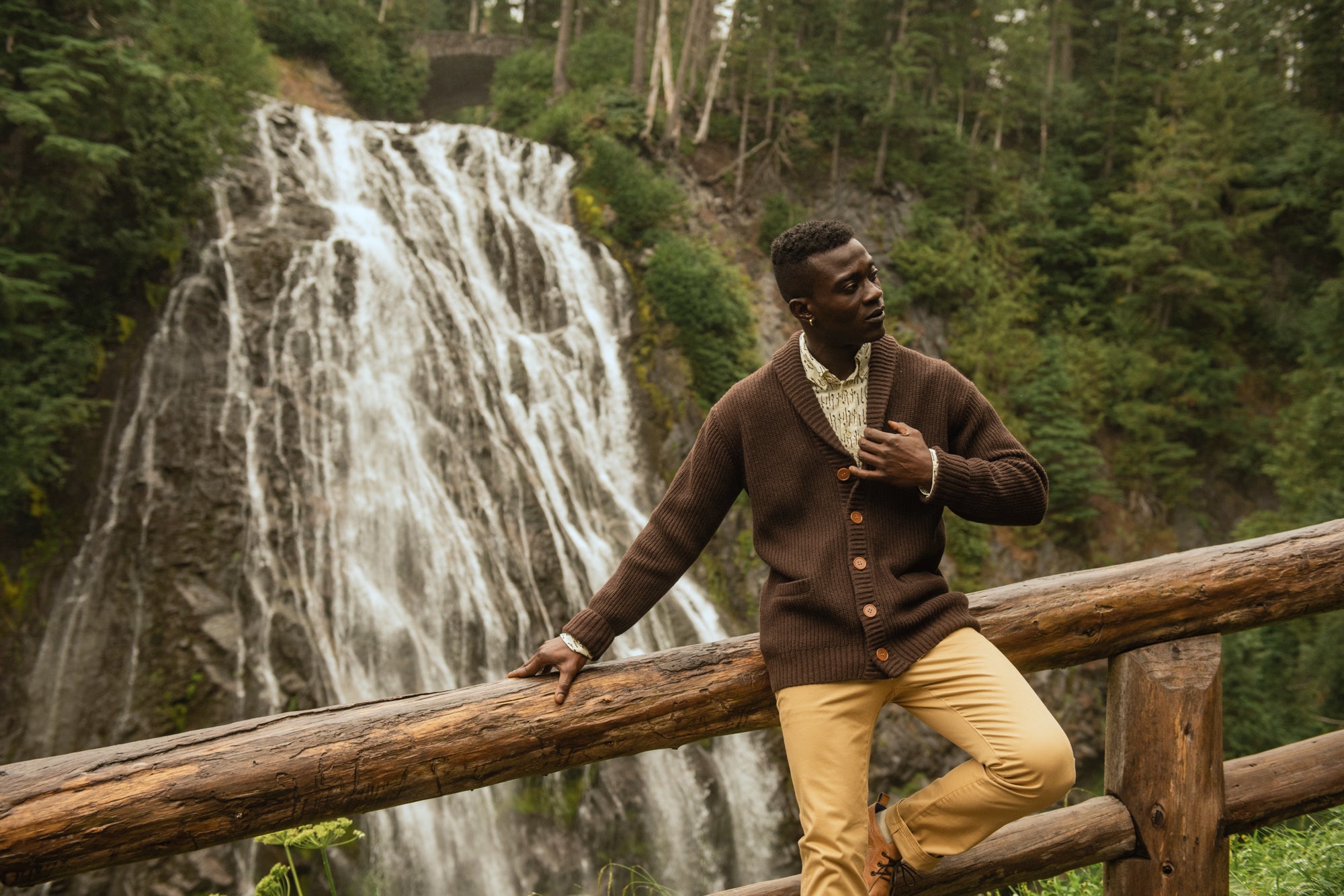 Person wearing cardigan in front of a waterfall 