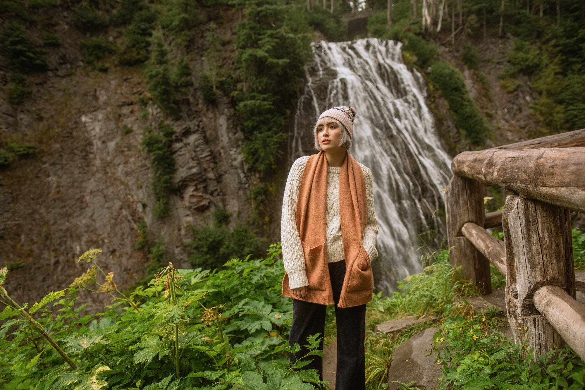 Person wearing scarf and toque in front of a waterfall