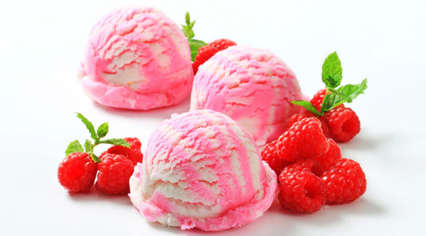 Three scoops of pink and white sherbet with raspberries for garnish