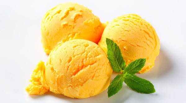 Three scoops of orange sorbet garnished with a trio of mint leaves