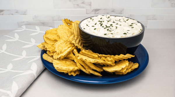 Black Calicle bowl filled with onion dip with ripple chips for dipping