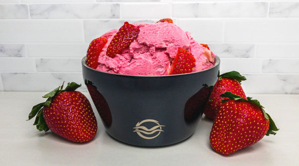 Strawberry ice cream topped with fresh strawberries in a black Calicle insulated ice cream bowl