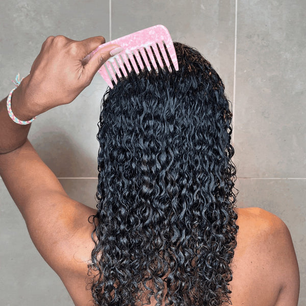 Girl with curly hair in shower using a wide tooth comb
