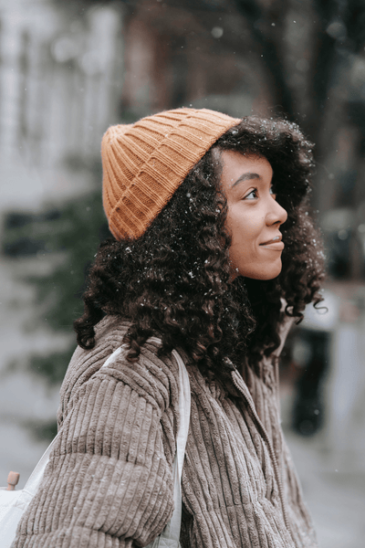 Black girl with curly hair and winter hat in the snow