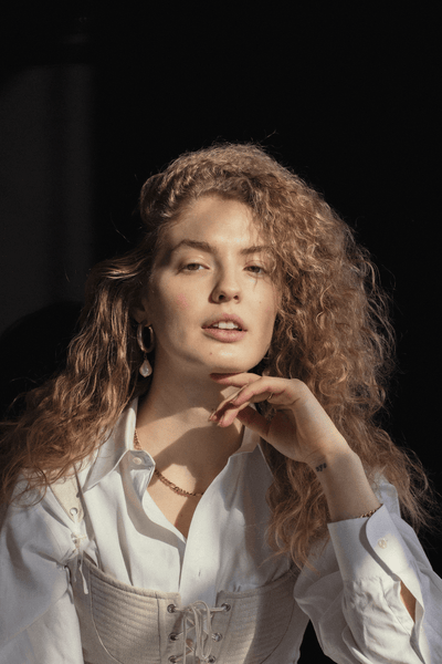 Girl with long blonde curly hair and white shirt