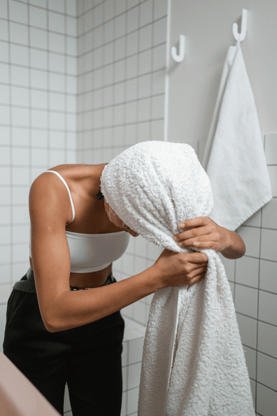 Woman in shower wrapping hair with white towel