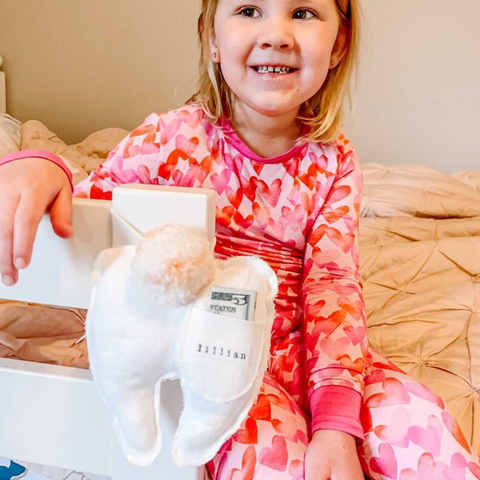 little girl receives  money in her tooth fairy pillow from the tooth fairy