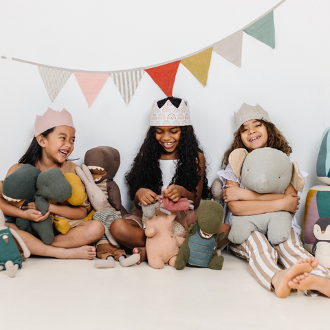 three girls playing dress up with crowns and stuffed animals