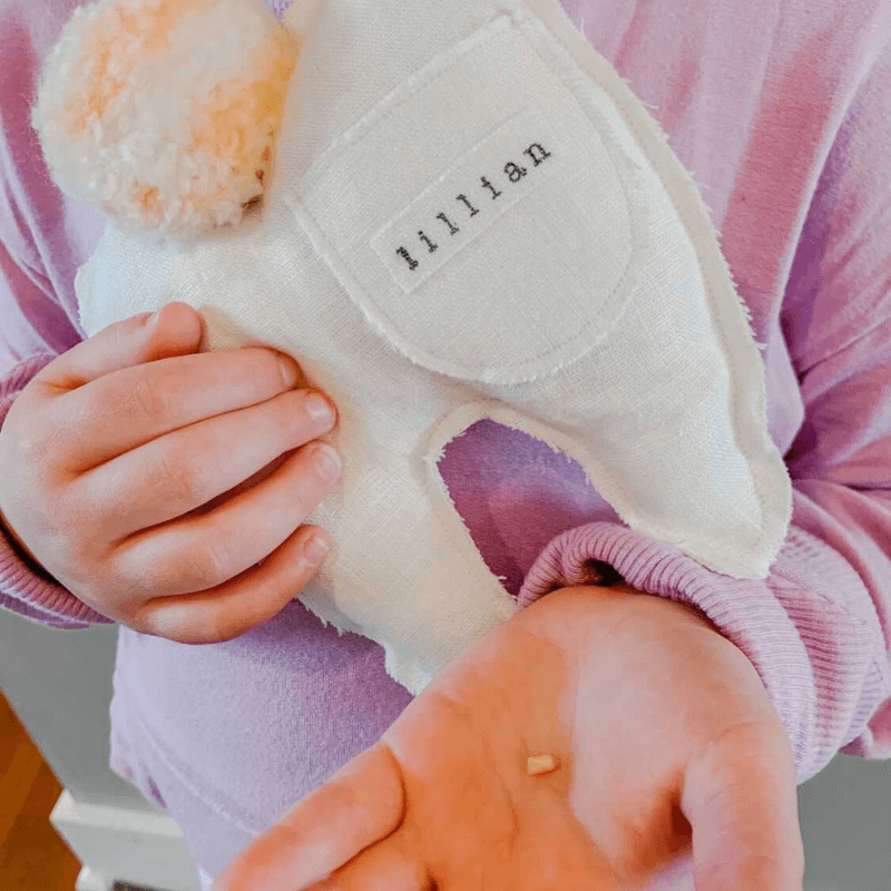 little girl holding her lost tooth with a personalized tooth fairy pillow from etsy