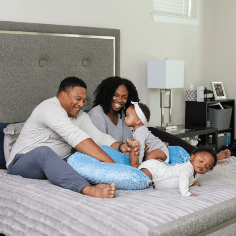 family sitting on a bed with twins using a twin z pillow
