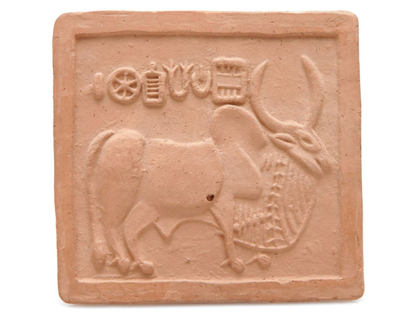 A closeup of tile sculpture blocks made by carving steatite stones into shapes. An ox and harvest vegetables are shown on the tile.