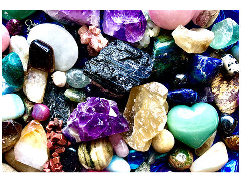 a large variety of use crystals in a picture including: purple amethyst, black tourmaline, green aventurine, moonstone, ocean jasper, labradorite, rose quartz, azurite, lapis lazuli, citrine, selenite, red jasper, and Dalmatian jasper