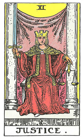 The figure on the card wears a crown with a small square on it, a red robe with a green mantle and a white shoe poking out from her robe. She holds a gold scale in her left hand, and a sword in her right hand, ready to dispense justice.