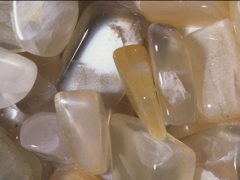 A collection of yellow moonstone and peach moonstones that are a traveler's stone.