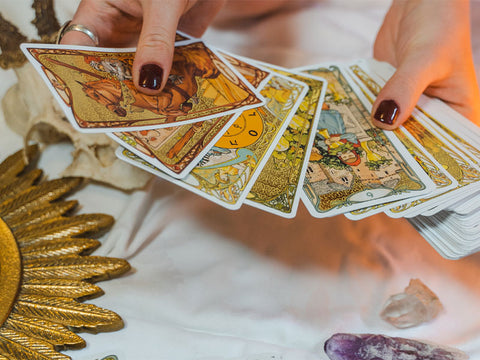 A person shuffling a gold tarot deck while doing a tarot reading