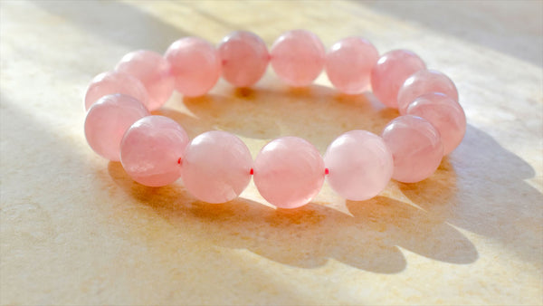 Rose Quartz Properties perfect for inviting love into your life. A Rose Quartz bracelet is displayed.