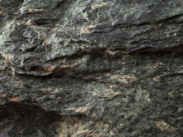 A closeup of dark grey steatite in situ used to carve and create molds as it's high talc content makes it very soft.