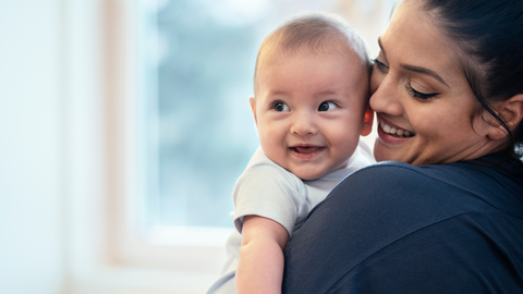 mom holding baby and smiling