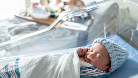 newborn baby in hospital wearing blue beanie