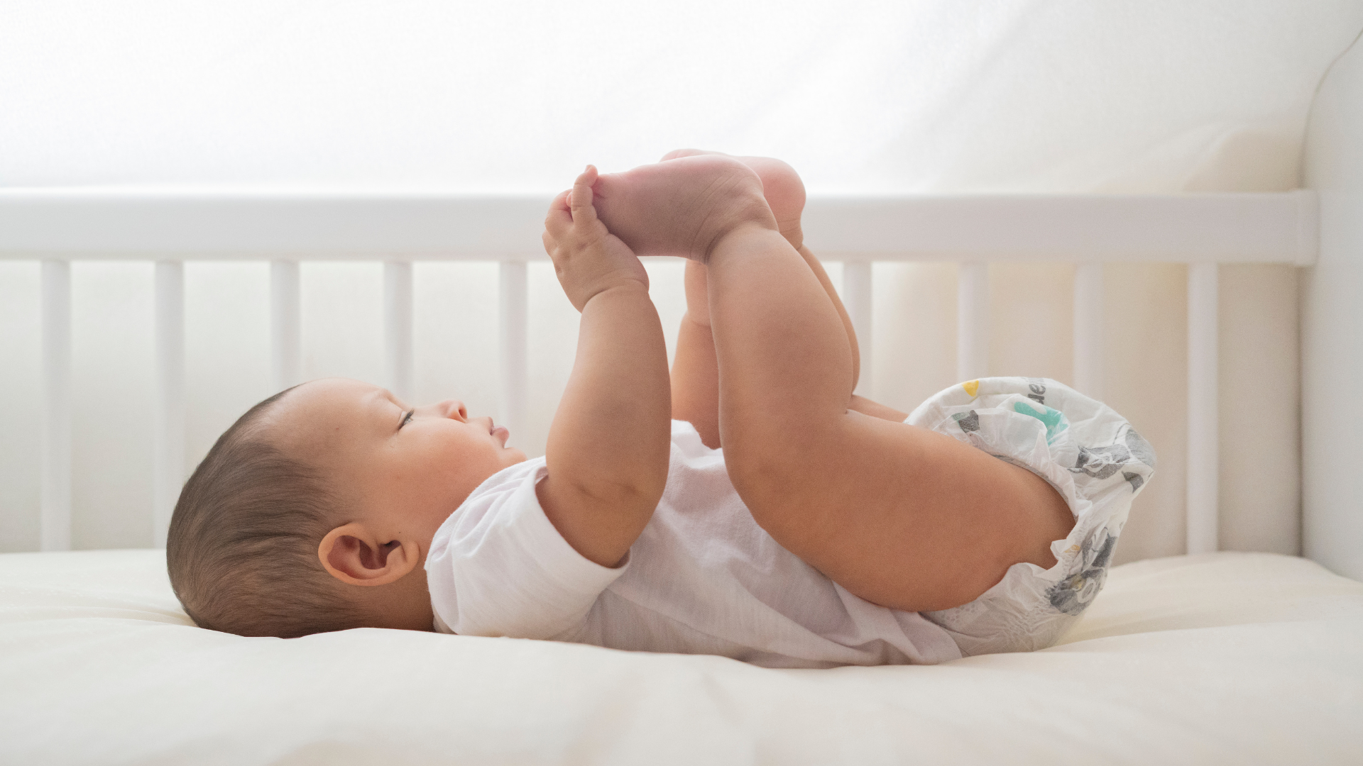 6 month old baby holding legs up in the air