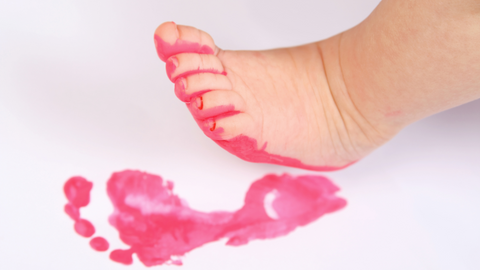 baby with paint on foot making footprint art