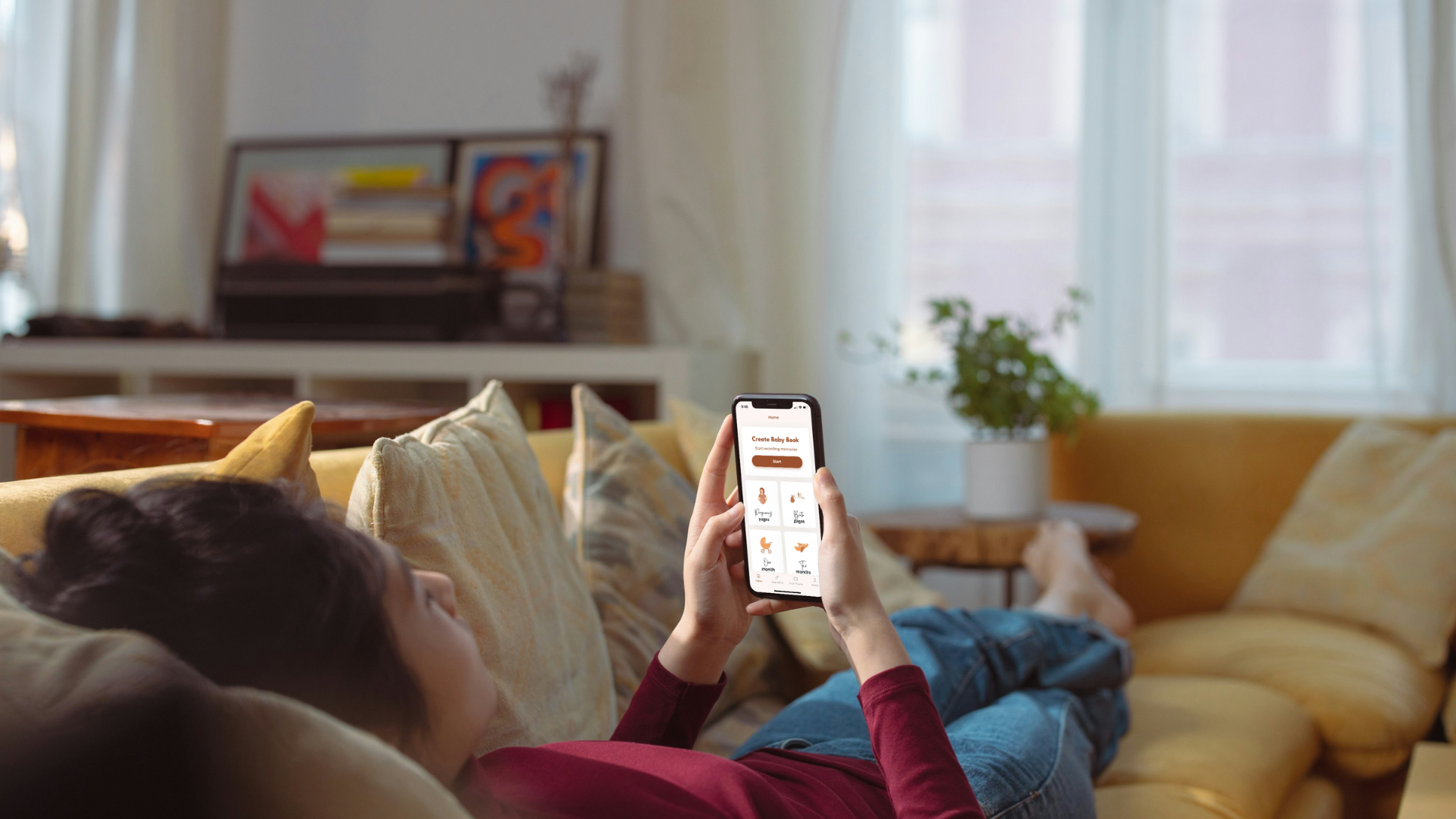 woman laying on couch making baby book on app