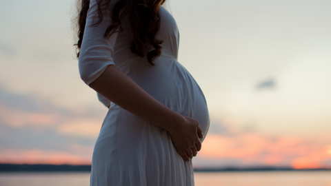 pregnant lady holding bump at sunset