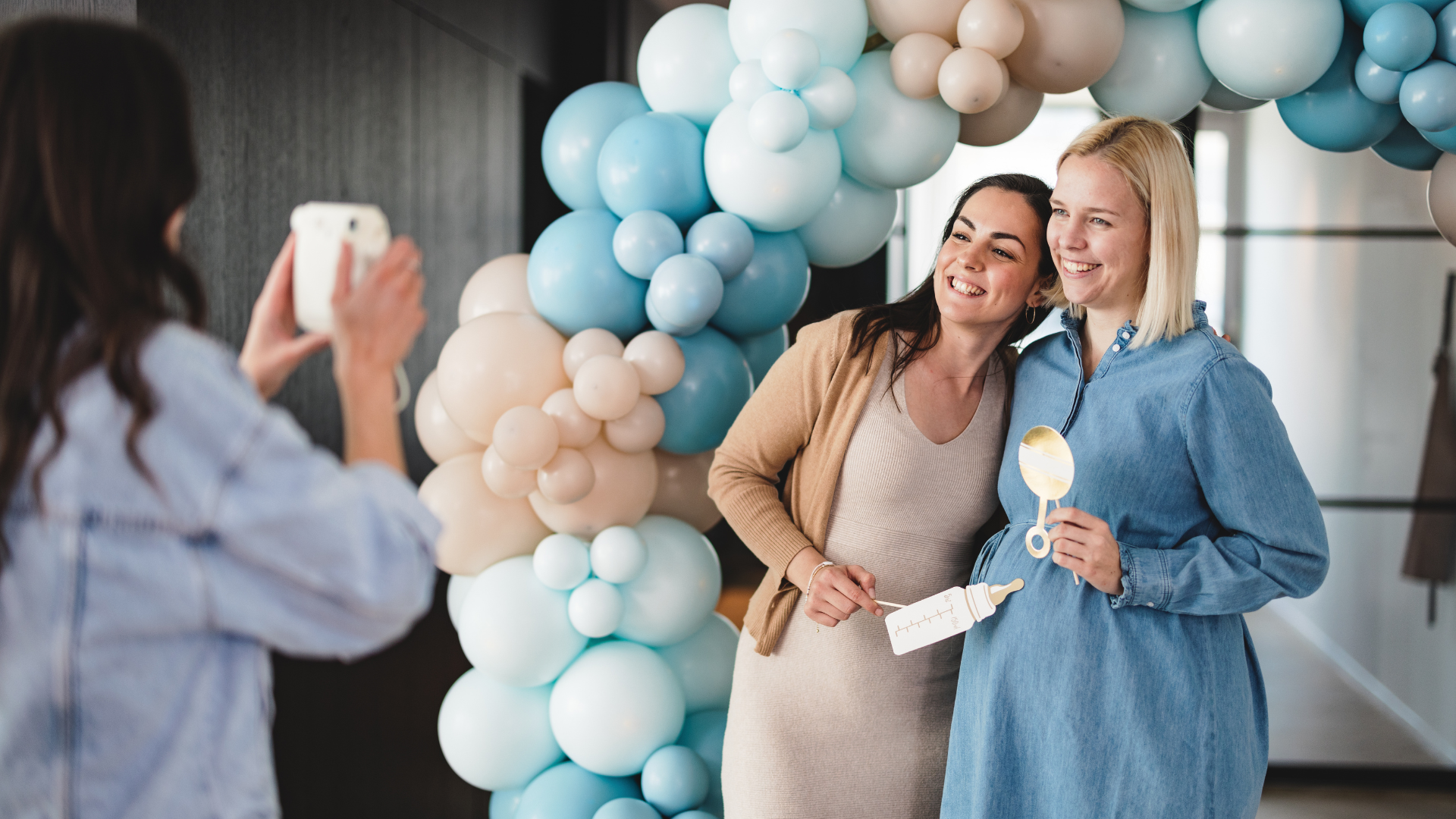 friend taking photo with pregnant lady at baby shower