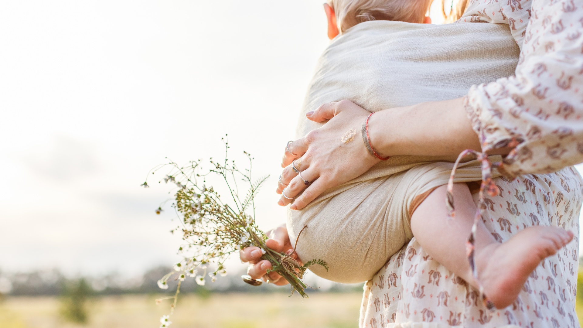 mom holding baby with flower in hand outside