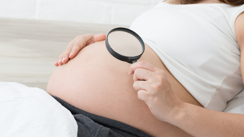 mom holding magnifying glass to pregnant belly