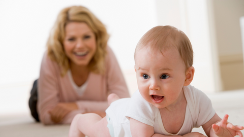 mom watching baby learn how to crawl