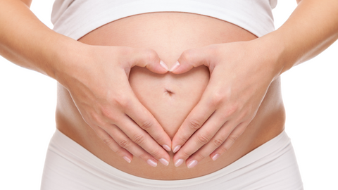 pregnant lady putting hands over bump shaped heart