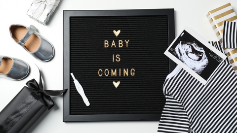 baby announcement board with ultrasound photo and baby clothes