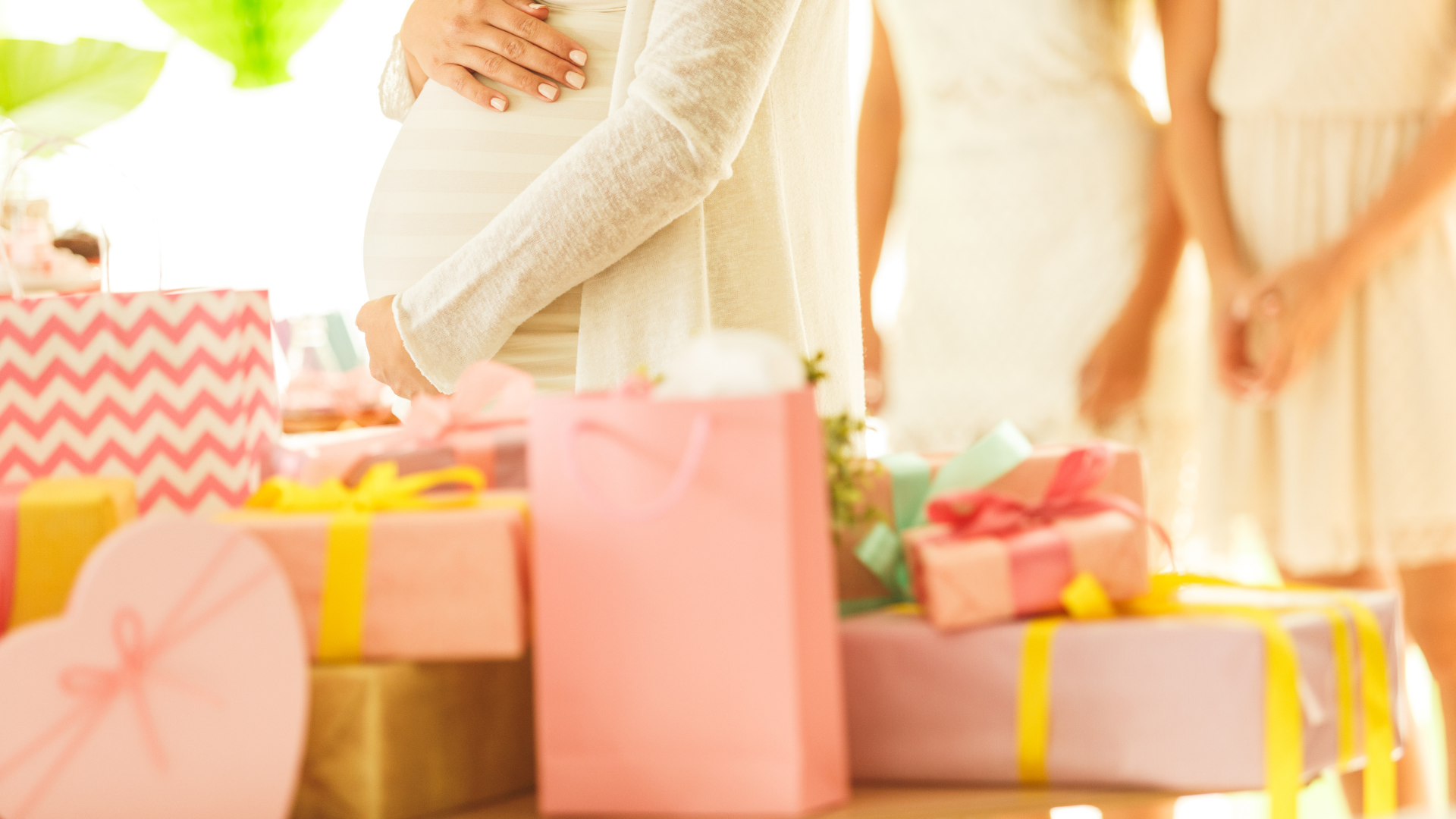 pink themed baby shower with mom to be in background holding bump