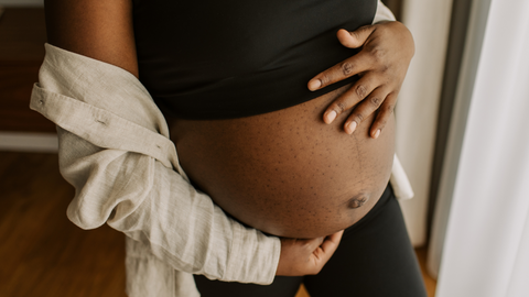 pregnant lady holding onto bump in bedroom